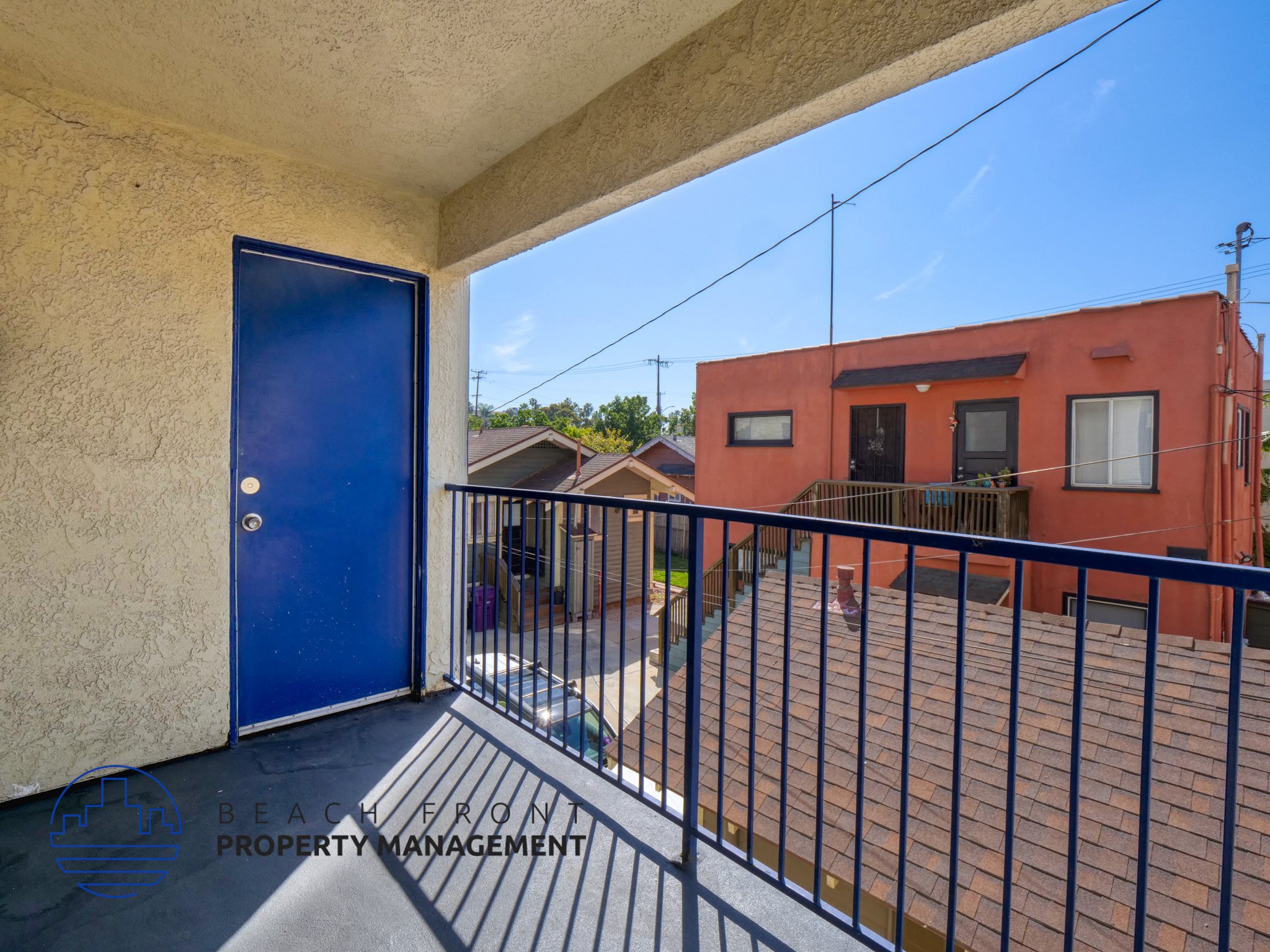 A balcony with a blue door and a black railing.
